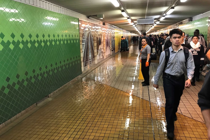 Commuters attempt to make their way through Devonshire Street Tunnel as half of passageway is blocked off due to rising water.