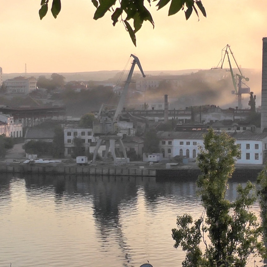 Smoke rises from a shipyard.