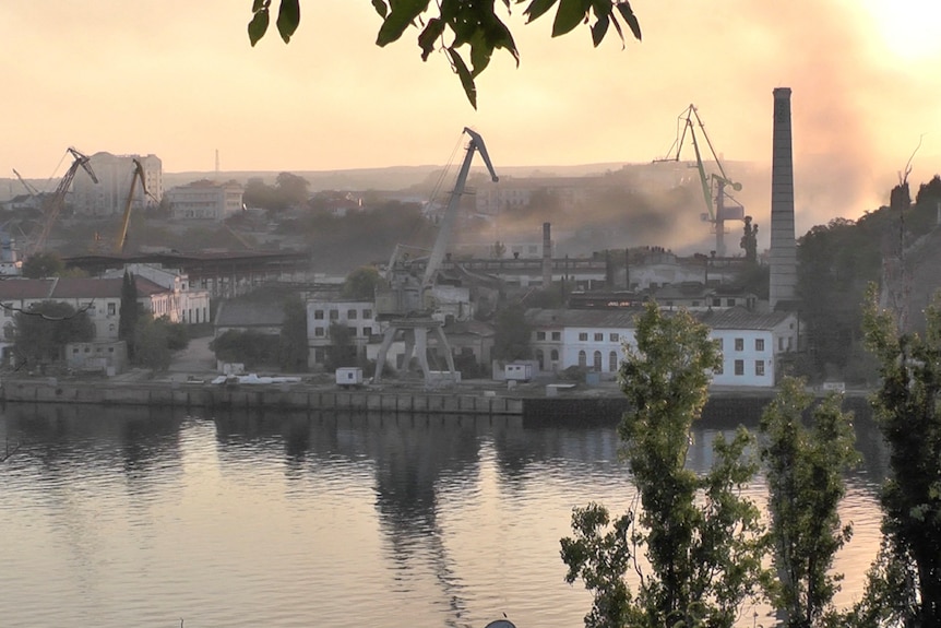 Smoke rises from a shipyard.