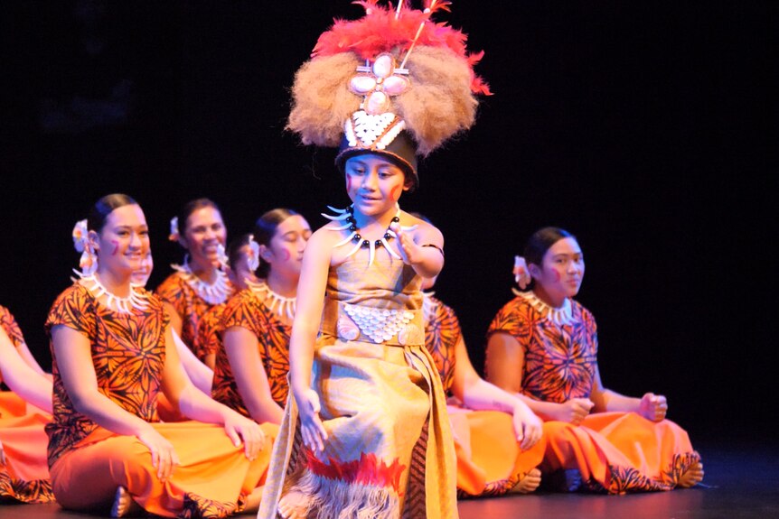 Young girl with traditional cloth mat dress and furry pink head dress performing on stage