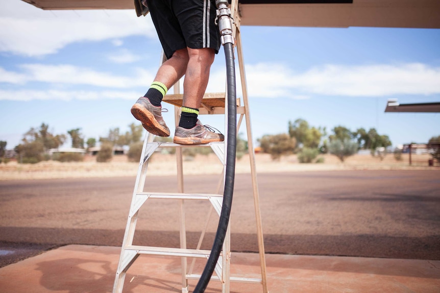 A man refuels a small plane at Warburton airstrip, WA.