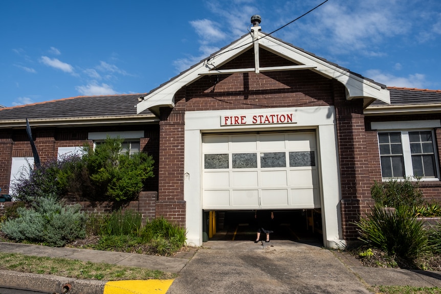 Exterior of a former fire station where a woman's feet can be seen underneath a rollerdoor