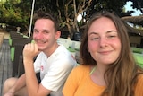 A young couple sitting outside smiling