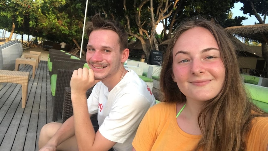 A young couple sitting outside smiling