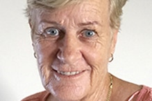 An older woman smiling at the camera in front of a white background