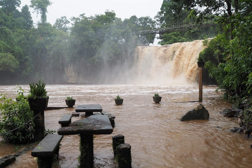 Mena Creek Falls flowing with a moderate amount of water.