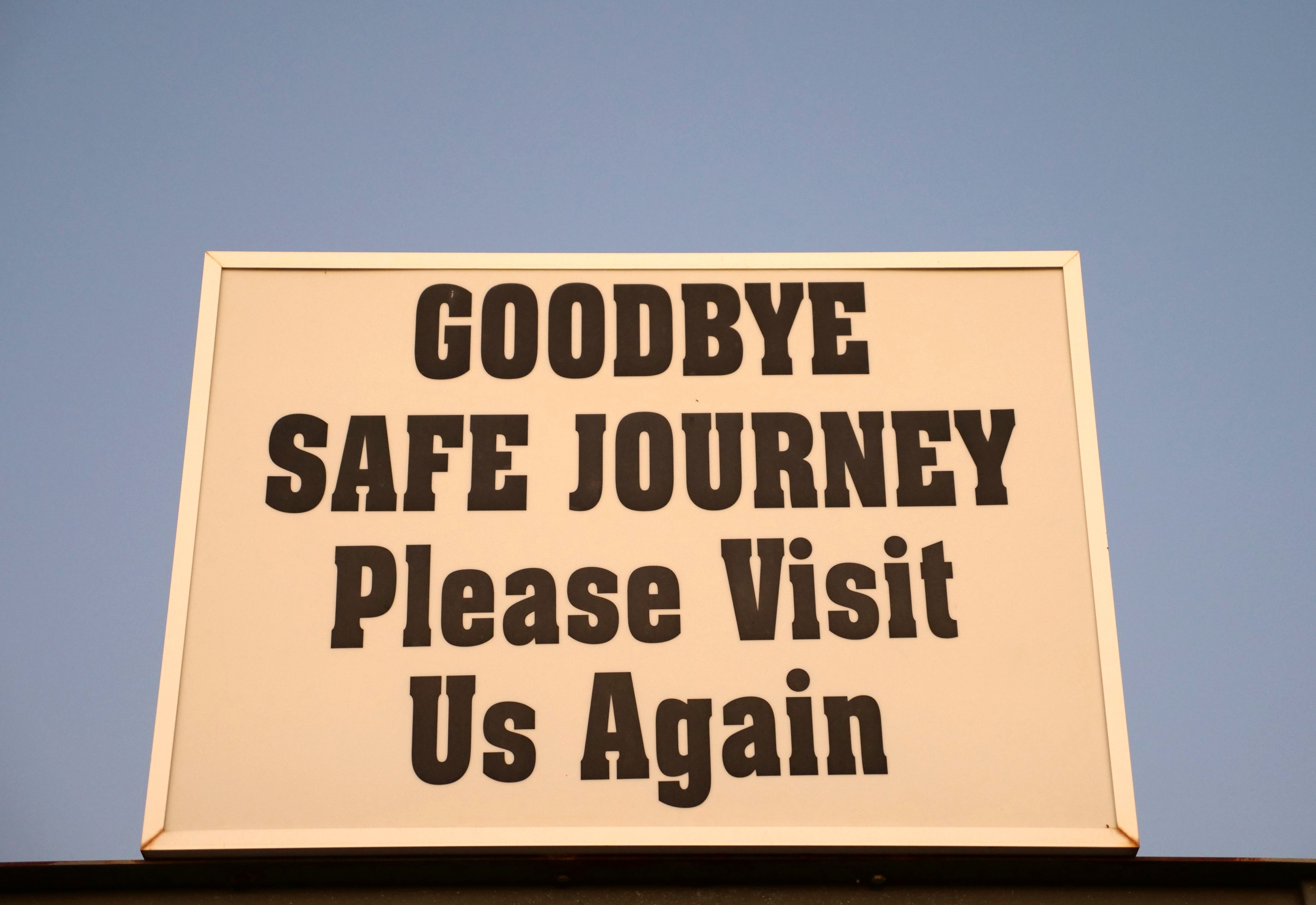 Uma placa dizendo adeus, esperamos que você nos visite novamente. 