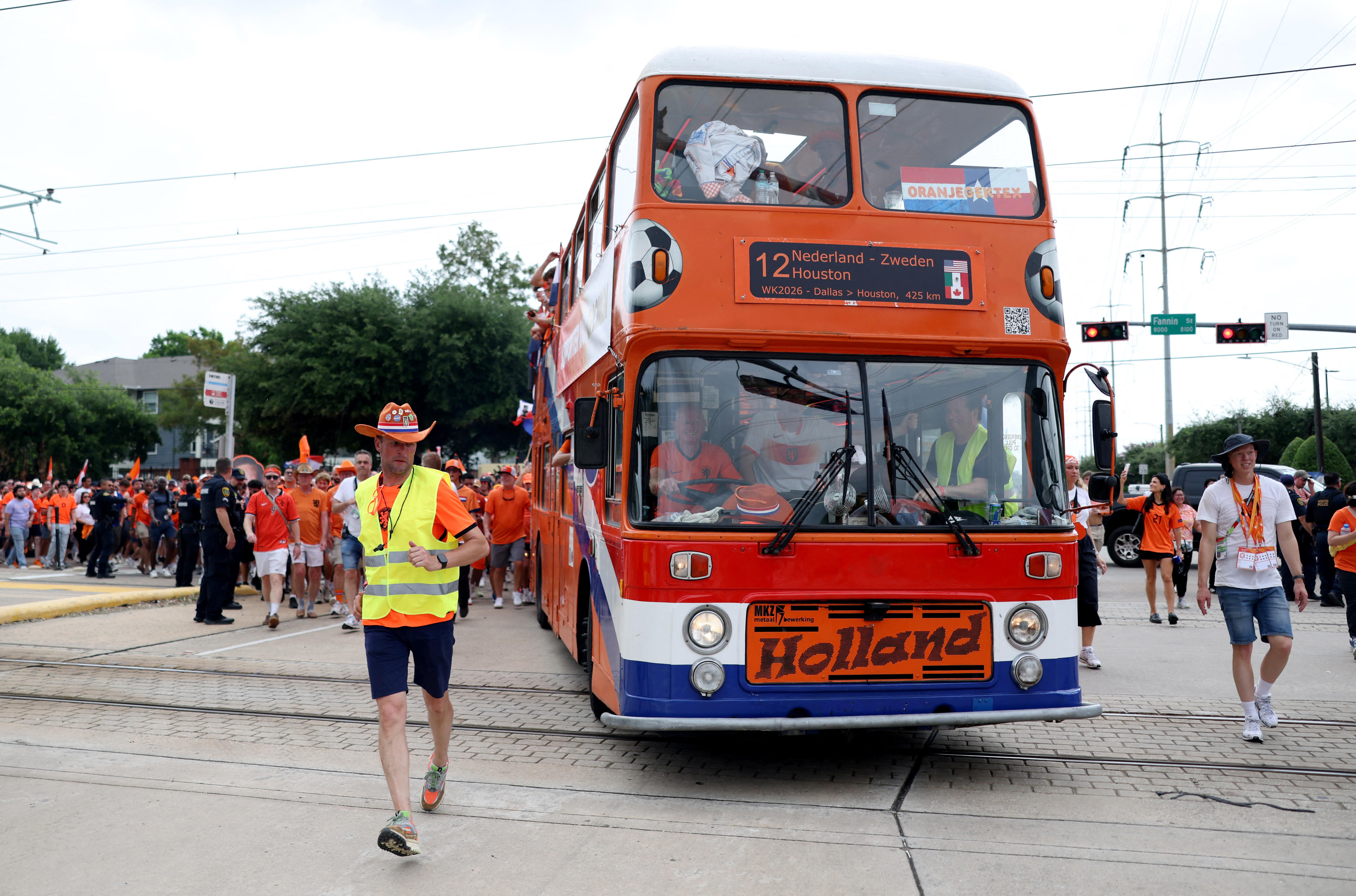 Netherlands fans wearing orange with their fan bus driving in front of them