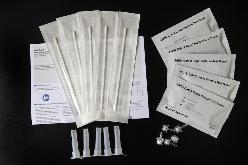 Five rapid antigen tests laid out on a black background.