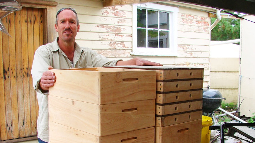 Beekeeper Andrew Matthewson stands behind a stack of new lids and supers made from macrocarpa pine milled on Flinders Island