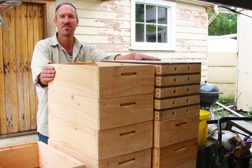 Beekeeper Andrew Matthewson stands behind a stack of new lids and supers made from macrocarpa pine milled on Flinders Island
