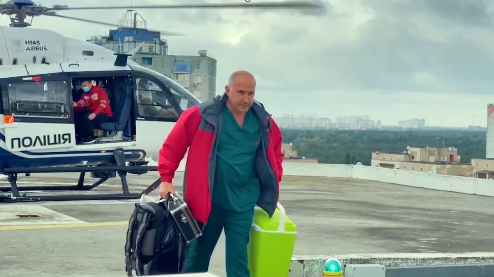 Un médico saliendo de un helicóptero que transportaba a un donante de órganos verde en una pista. 