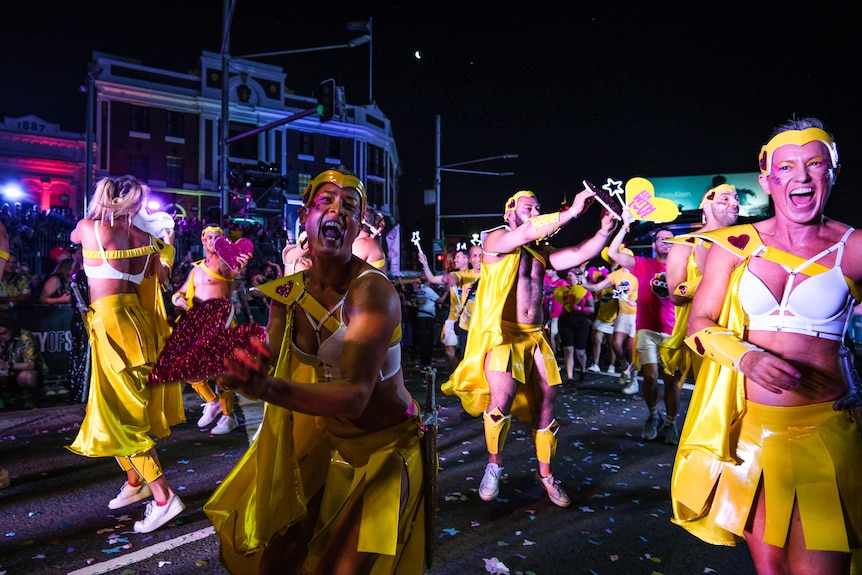 Un groupe de personnes vêtues de latex jaune danse dans la rue