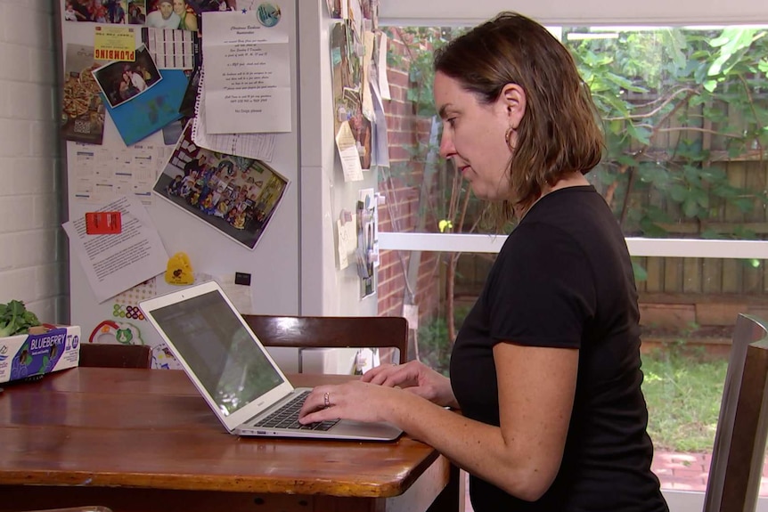 Brigid Cottrill sitting at her kitchen table using her laptop computer