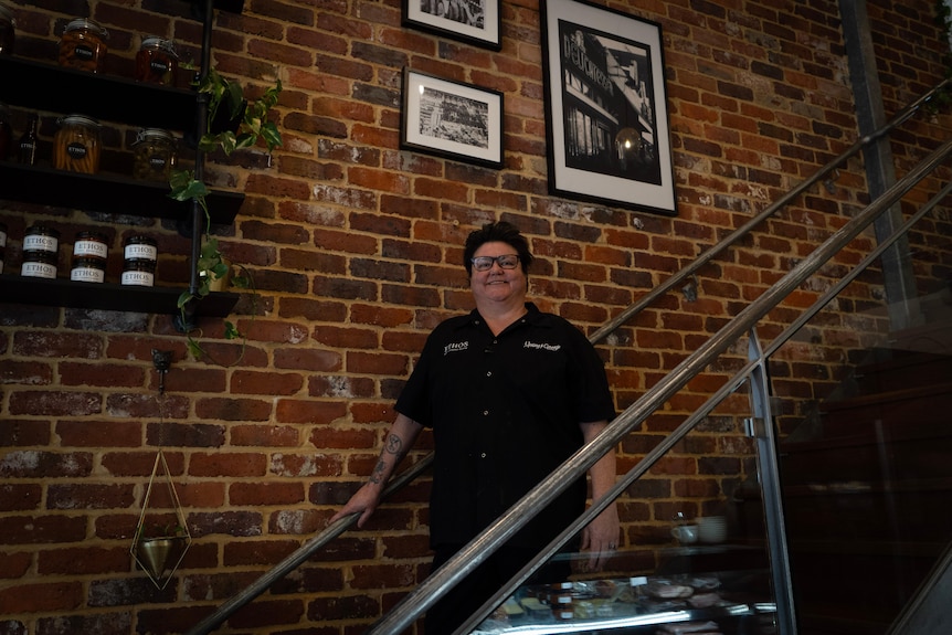 A woman in a black chef uniform staring on a stairway. 