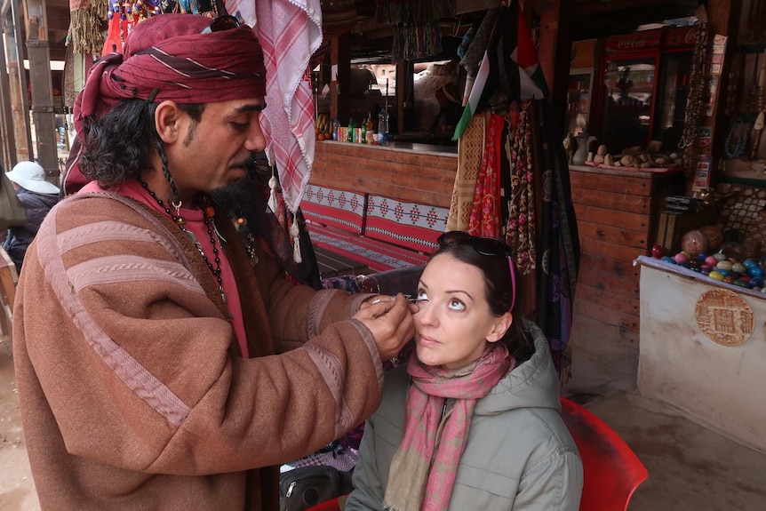 Travel writer Rachel having kohl painted around her eyes in Jordan.