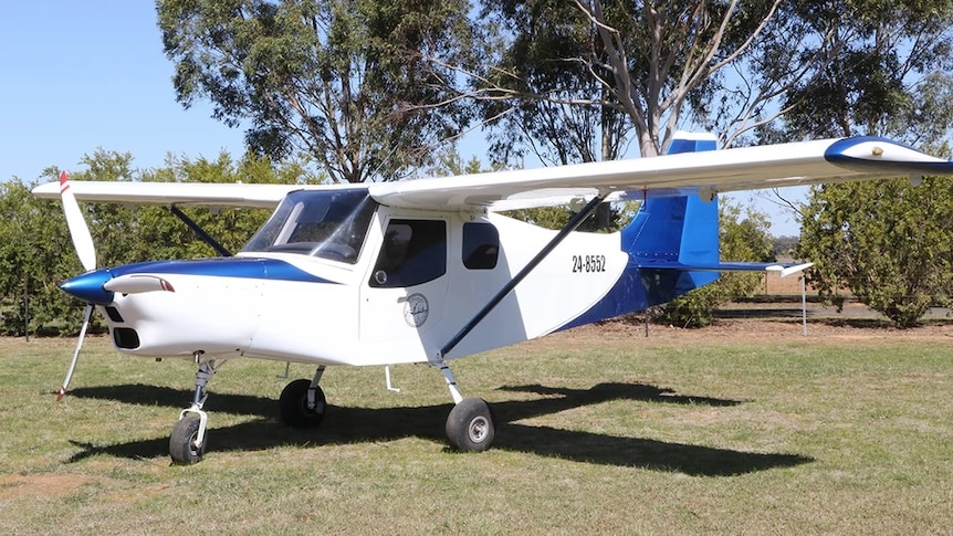 A Brumby 610 light plane parked on the ground. Trees are in the background.