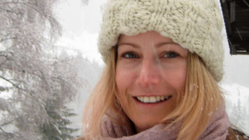 A smiling woman stands outside in the snow.