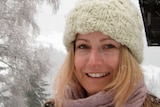A smiling woman stands outside in the snow.