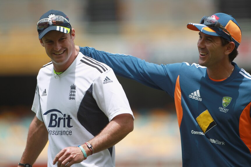 England cricketer Andrew Strauss, in white warm-up gear, is touched on the shoulder by Australian assistant coach Justin Langer.