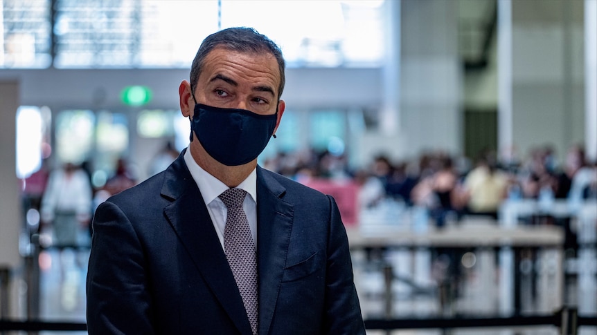 A man in a suit wearing a black face mask