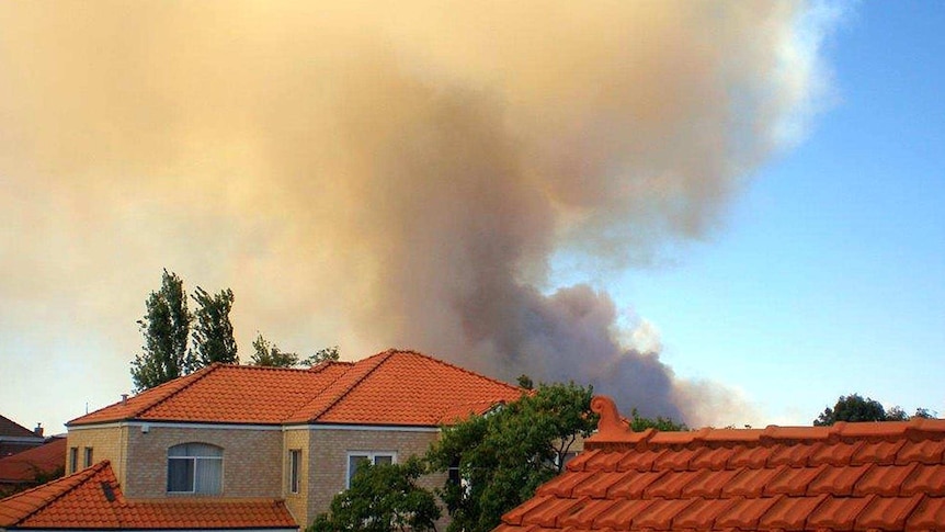 Smoke from a bushfire rises over houses at The Vines.