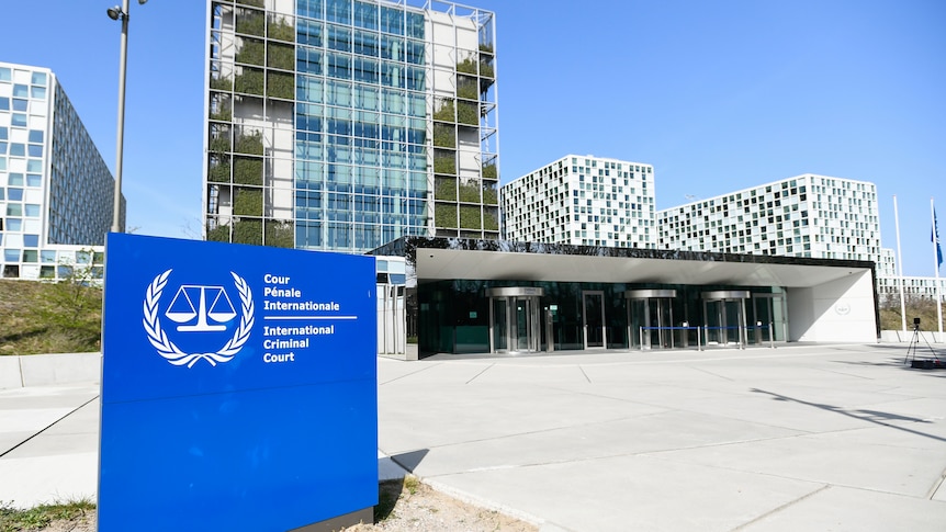 A blue sign with the International Criminal Court logo out the front of a large building.