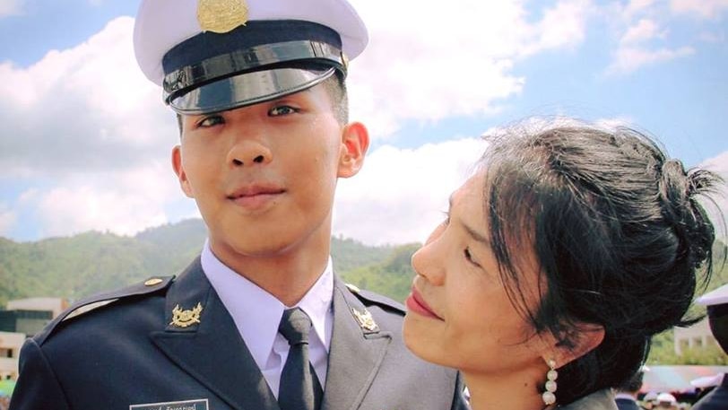 young army cadet in uniform stands beside his mother