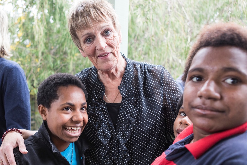 A woman and several young people pose for a photo.