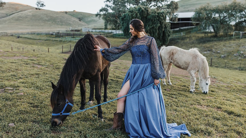 Photo of woman in a gown with two horses.