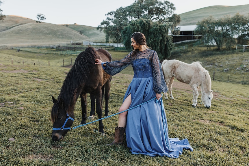 Photo of woman in a gown with two horses.