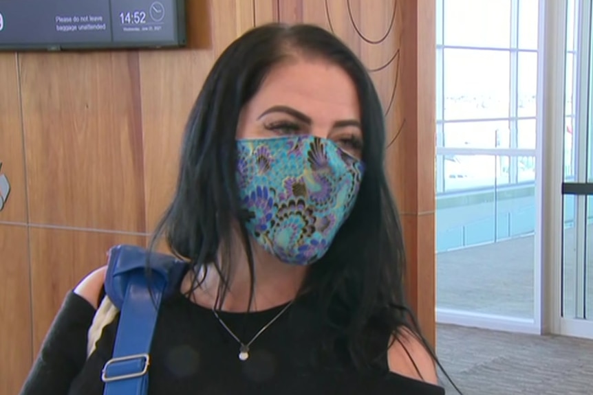 A woman with black hair wearing a blue face mask at Adelaide Airport
