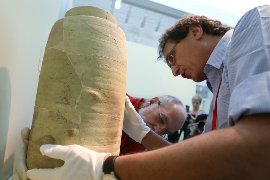 A man holding a large earthenware jar