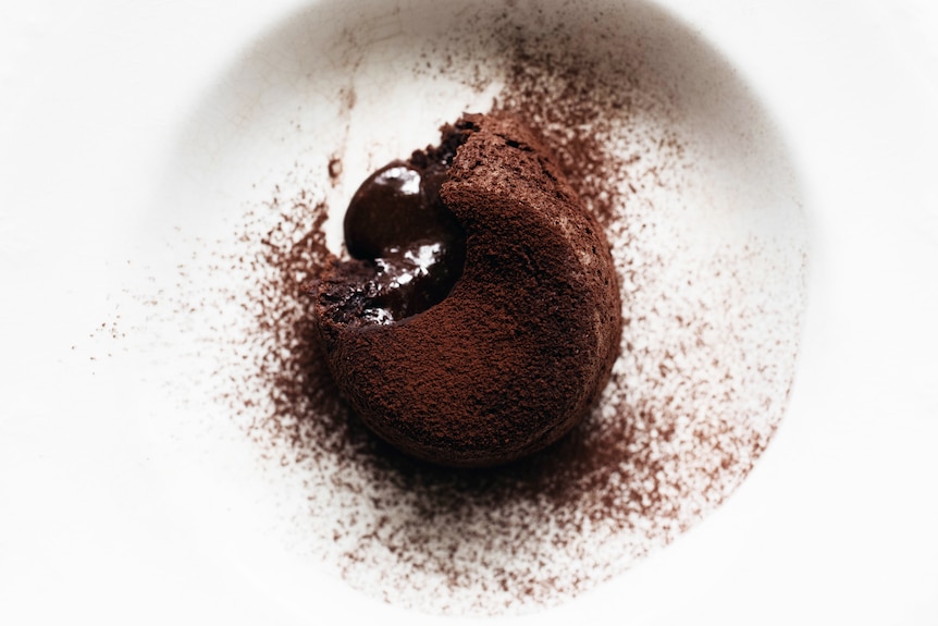 An individual chocolate pudding with a melted chocolate middle, topped with cocoa powder, a simple make at home dessert.