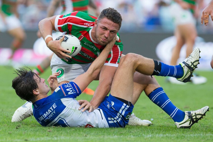 Lachlan Lewis lies on his back and holds on to Sam Burgess by the throat, Burgess has the ball in one hand
