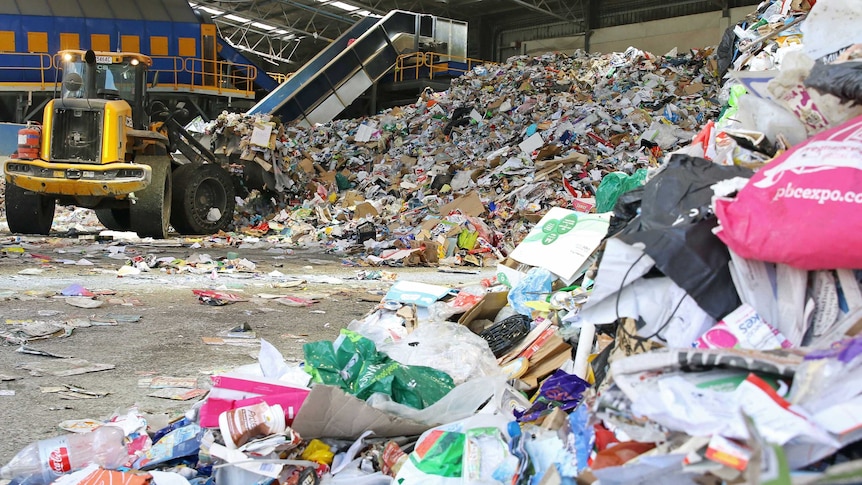 Tractor separates material for recycling at a facility.