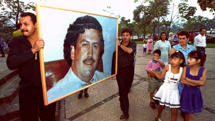Two men carry framed photo of late Pablo Escobar