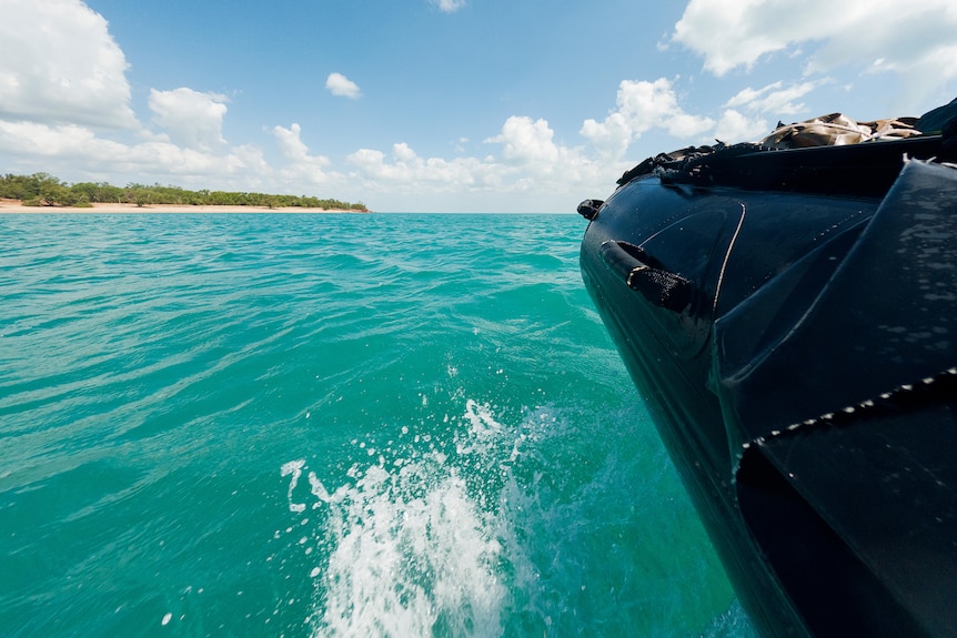 black inflatable boat travelling along bright blue ocean