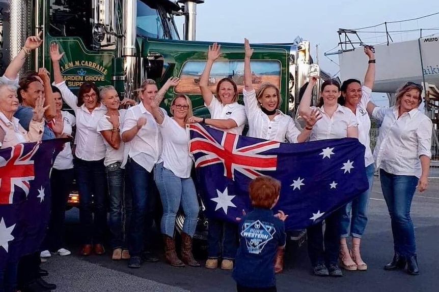 Many women with an australian flag standing in front to a truck