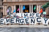 Activists hold a sign reading climate emergency alongside Sydney Lord Mayor Clover Moore.