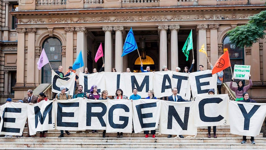 Activists hold a sign reading climate emergency alongside Sydney Lord Mayor Clover Moore.