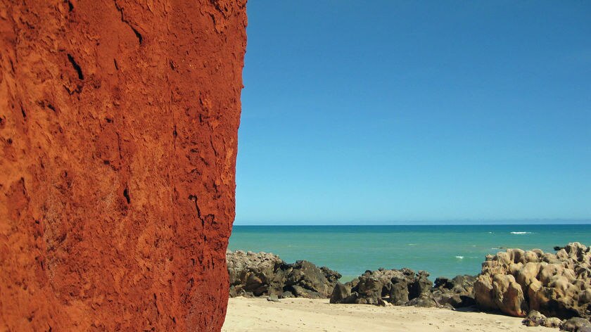 A red cliff next to a sandy beach and blues sea at James Price Point north of Broome.