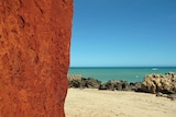 A red cliff next to a sandy beach and blues sea at James Price Point north of Broome.