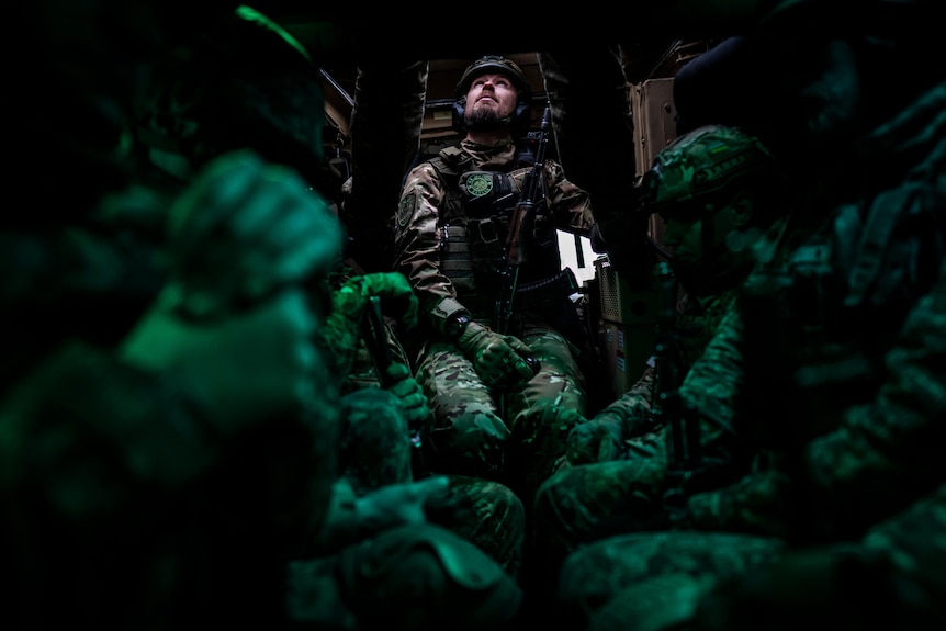 Members of the Ukrainian National Guard look up while dressed in military uniforms.