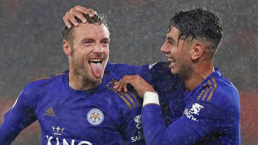 Leicester City player Ayoze Perez rubs the head of Jamie Vardy, who has his tongue out in the rain.
