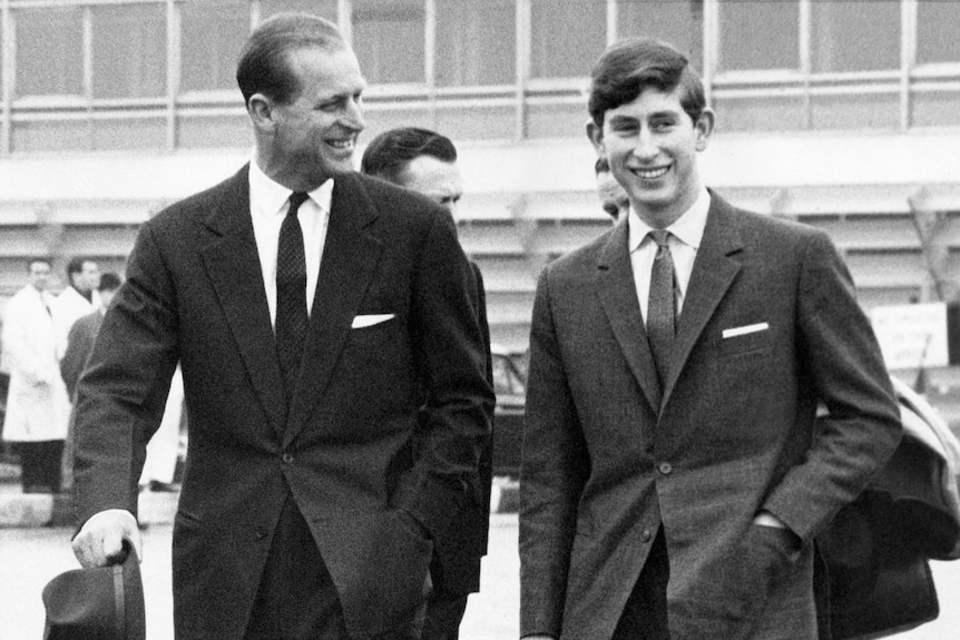 Prince Philip laughs with his son, Prince Charles, as they both walk on the tarmac.