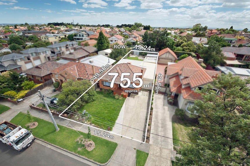 An aerial photo shows a square orange-brick house nestled amid similar homes as you see a sea of orange rooftops to the horizon.