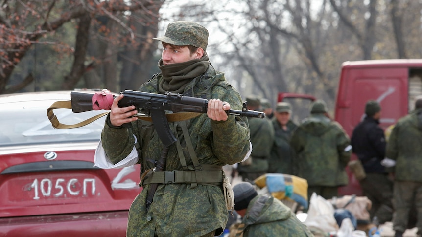 A soldier holds a gun while patrolling a street. 