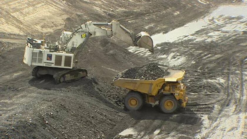 Generic TV still of large yellow mining truck being loaded up with coal from Qld mine