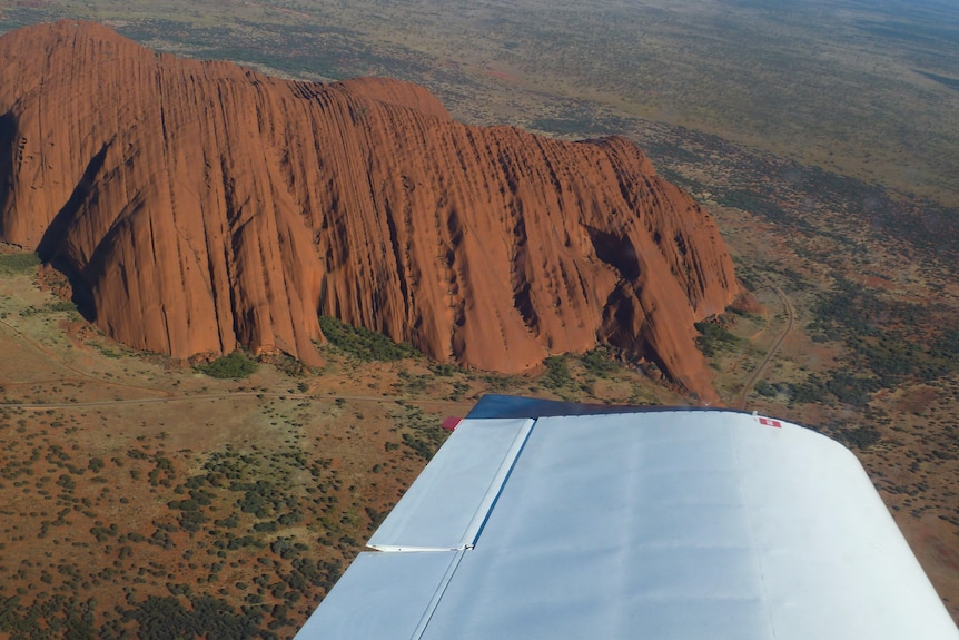 Uluru viewed from above with a plane wing.